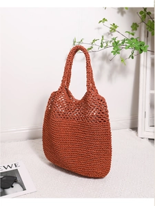 Close-up of burnt orange woven straw tote bag with intricate hollow mesh pattern