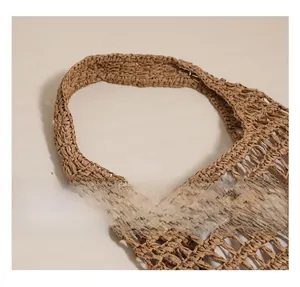 Close-up of wide shoulder strap on a brown hollow out straw woven tote bag texture