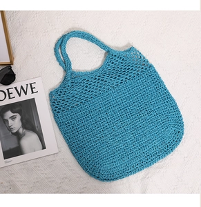Flat lay of blue hand-woven hollow-out tote bag with stylish summer beach accessories