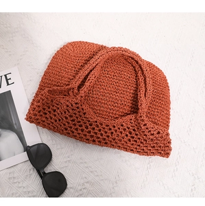 Macro detail of terracotta woven straw tote featuring dense knit and openwork mesh design