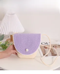Close-up of woven crossbody bag featuring a purple flap and central faux pearl detail
