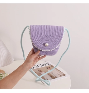 Close-up of hand-woven purple straw bag with white wavy trim and a pearl button accent