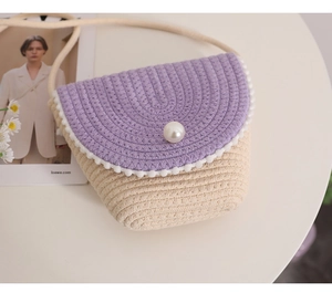 Detail of handmade straw crossbody bag with purple flap and large pearl decoration