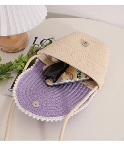 Detail of woven straw crossbody bag showing purple interior lining and storage space