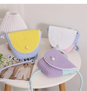 Detailed overhead view of woven straw crossbody bags with pearl buckles on a white table
