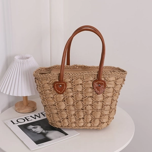 Handwoven straw tote bag with quilted diamond pattern and brown leather heart handles