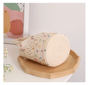 Detail of handwoven cream bucket bag with colorful pom-poms on an octagonal tray