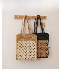 Détail de la texture crochet ajourée sur sacs cabas bicolores suspendus à des crochets