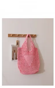 Detail showing the pink hollow out straw tote bag with hand-knitted mesh and triangle pattern