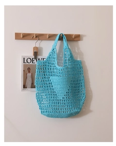 Detail view of a bright blue crochet tote bag with open-knit mesh texture and handles