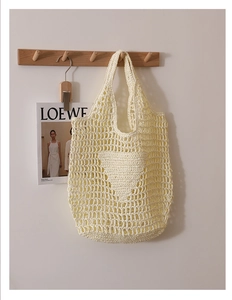 Close-up of handmade off-white woven tote bag with hollow heart crochet pattern