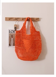Detail of orange woven straw tote bag featuring hollow knit and iconic triangle pattern