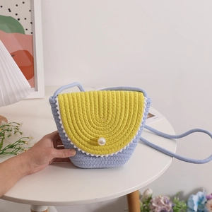 Blue and yellow straw crossbody bag with white pom-pom trim and pearl buckle