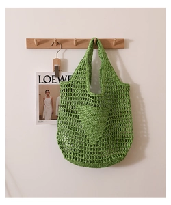 Detail of green crochet tote bag featuring hollow heart pattern on textured straw weave