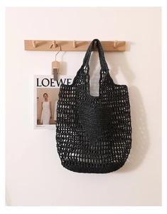 Detailed view of black woven straw tote bag featuring intricate hollow mesh patterns