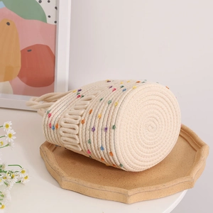 Handmade woven bucket bag with colorful polka dots on a cream octagonal tray
