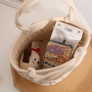 Chic cream woven basket bag with colorful pom-poms showing spacious interior capacity