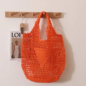 Large bright orange woven hollow straw tote bag for beach vacations with shoulder strap