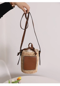 Detail der handgewebten Stroh-Beuteltasche mit braunem Lederpatch und Kordelzugbeutel