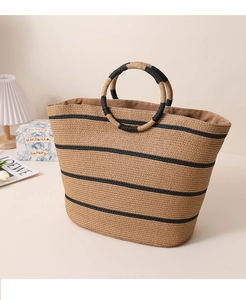 Detail of round ring handles on a striped straw tote bag for summer beach holidays