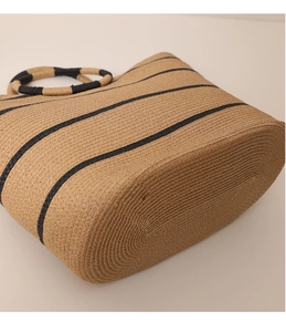 Macro view of woven straw tote texture with black stripes and thick oval base design