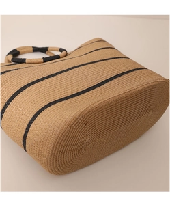 Detail view of woven straw tote bag bottom with stripes and natural texture finish