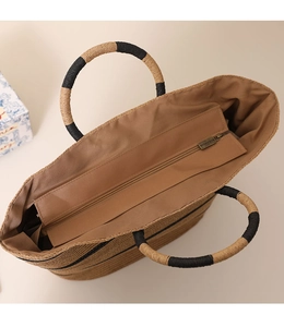 Macro view of circular woven handles and striped straw tote bag with secure zip closure