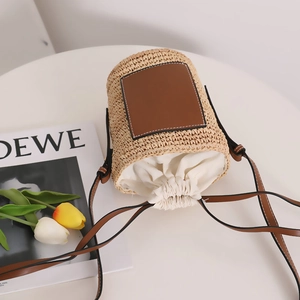 Stroh-Eimertasche mit braunem Lederpatch und weißem Kordelzug für den Strandurlaub