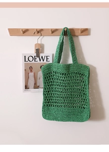 Close-up of grass green crochet tote bag with open hollow knit design and double straps