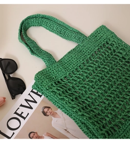 Detail shot of green hollow out woven straw bag with textured hand-knitted pattern