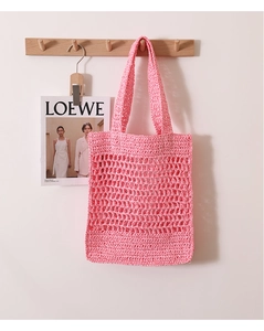 Detailed view of pink handwoven crochet tote bag with hollow mesh design hanging on wall