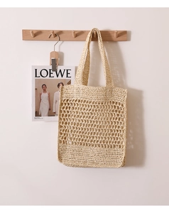 Detail of hand-woven beige straw bag featuring a large hollow mesh net structure