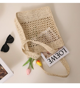 Detail of hollow mesh woven straw tote bag with sunglasses and fashion accessories