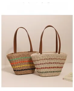 Detail of colorful striped straw tote bags with brown leather handles on neutral background