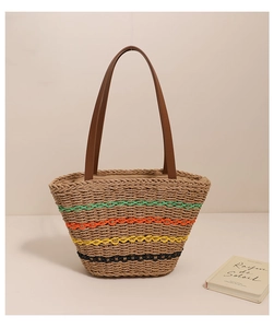Close-up of woven straw tote bag with multi-color wave stripes and brown leather handles