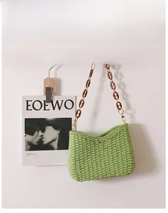 Close-up of light green straw bag featuring a vintage resin chain strap on a wall hook