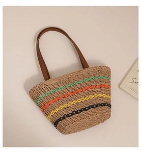 Detail view of woven straw tote bag featuring vibrant colorful wave patterns and leather handles