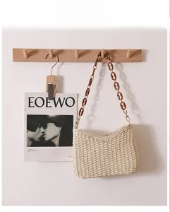 Close-up of beige woven straw tote bag with brown acrylic and metal chain strap