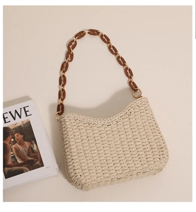 Detail of beige woven straw tote featuring amber chain strap and dense knit texture