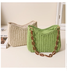 Detail of hand-woven straw tote bag with elegant resin and metal link shoulder straps