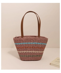 Detailed view of colorful woven stripes and dark brown leather straps on a straw tote bag