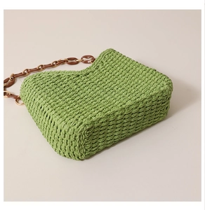 Detailed view of green woven tote with brown resin chain strap for summer vacations