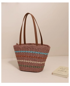 Detailed view of colorful striped straw tote bag with brown leather shoulder straps