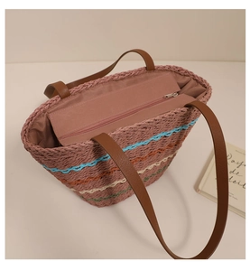 Detail view of colorful striped straw tote bag showing brown leather straps and zip closure