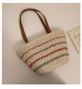 Detail showing the colorful woven stripes and brown leather handle of the straw beach tote