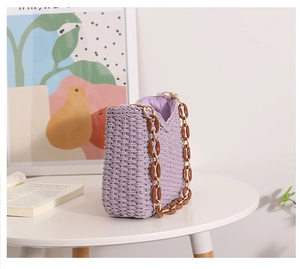 Detail view of purple woven tote bag with brown acrylic chain on a minimalist table