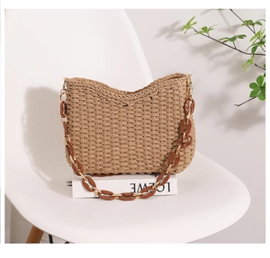Detail of hand-woven straw tote with resin chain strap on minimalist background
