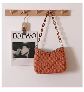 Detailed texture of rust red hand-woven shoulder bag with amber resin chain strap