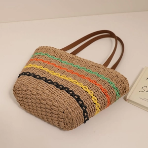 Large colorful striped straw tote bag with brown handles on a neutral tabletop