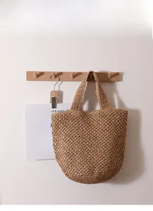 Dettaglio di una borsa a tracolla in paglia lavorata all'uncinetto con motivi floreali
